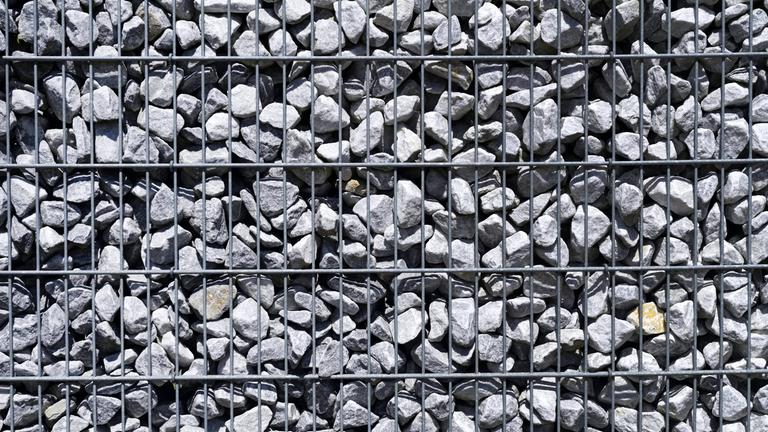 Gabione, eine Mauer aus Draht, in die Schottersteine eingefüllt sind. Nahaufnahme